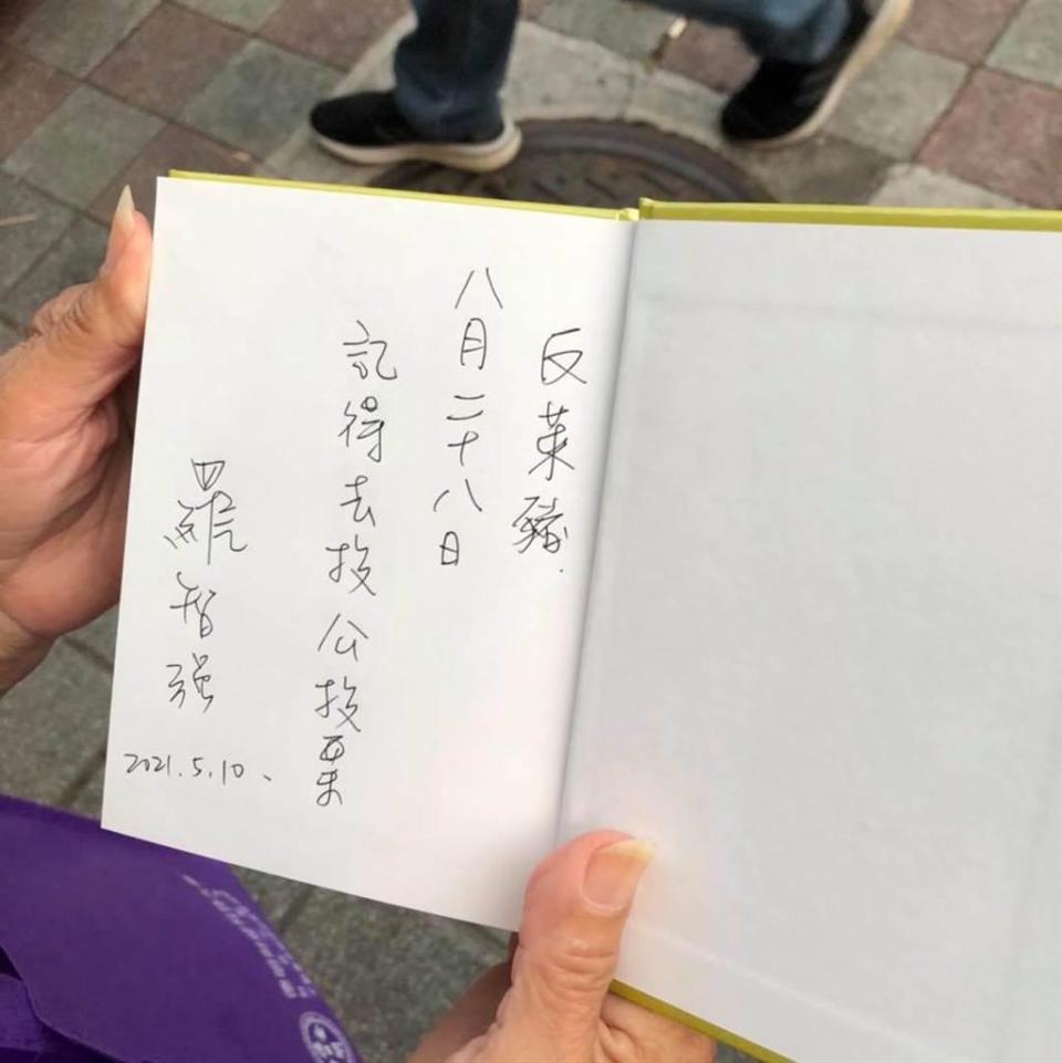 羅智強在民眾的書上簽名並寫下提醒，記得在8月的公投中投下反對萊豬的選票。(圖/翻攝自羅智強臉書)