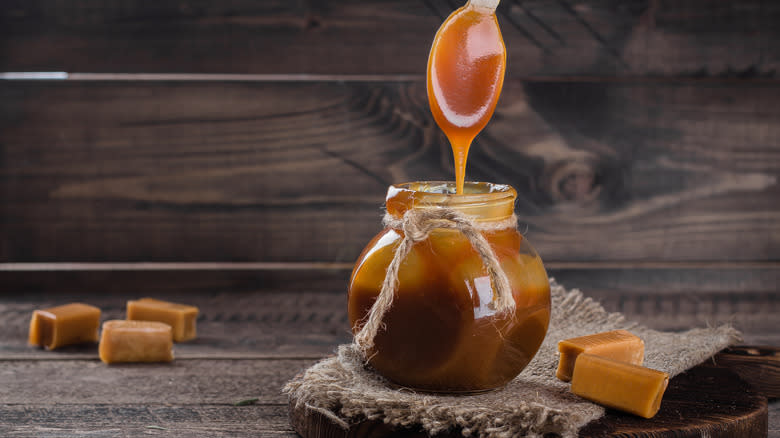jar of caramel sauce with caramel dripping from spoon