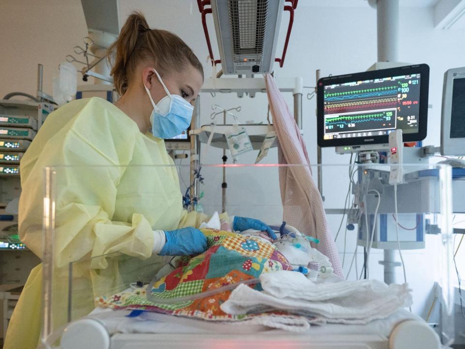 nurse in mask caring for baby in ICU