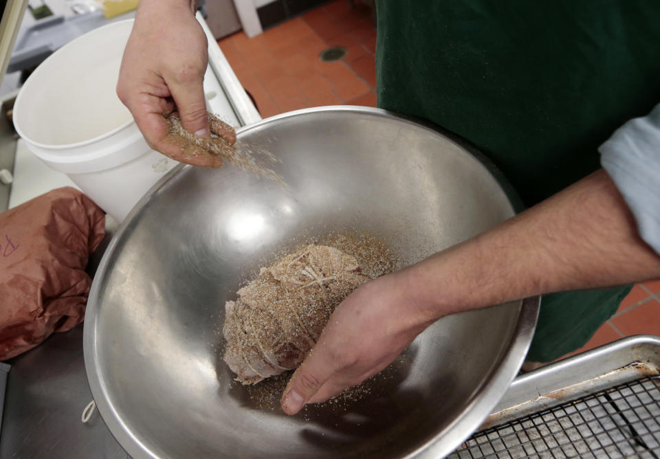 In this Dec. 11, 2013 photo, a beef top round, tied with pork back fat, is seasoned before being placed in the oven as part of the process of preparing the "spiced round," a Christmastime beef specially, at the Porter Road Butcher in Nashville, Tenn. The specialty meat, reminiscent of corned beef, has all but disappeared in recent decades amid changing tastes and the steady decline of local butchers to prepare it. (AP Photo/Mark Humphrey)