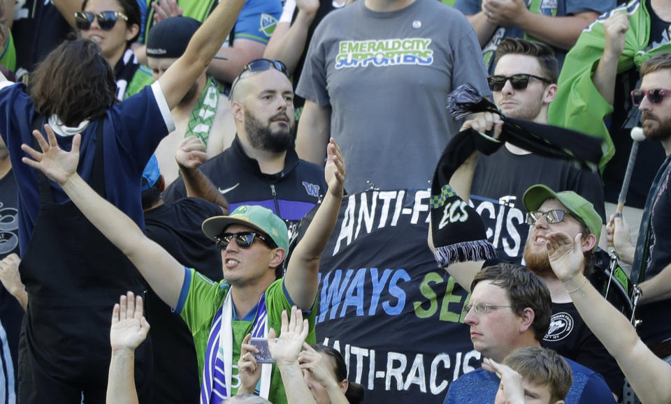 In this July 21, 2019, photo, a sign that reads "Anti-Facist Always Seattle Anti-Racist" is displayed in the supporters section during an MLS soccer match between the Seattle Sounders and the Portland Timbers in Seattle. Major League Soccer's new policy that bans political displays at matches is drawing attention in the Pacific Northwest, where supporters' culture is often intertwined with politics and social issues. (AP Photo/Ted S. Warren)