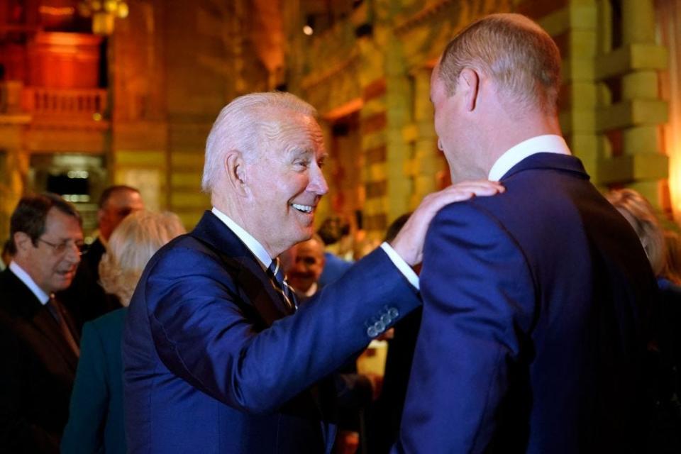 President Joe Biden smiles and puts a hand on Prince William's shoulder