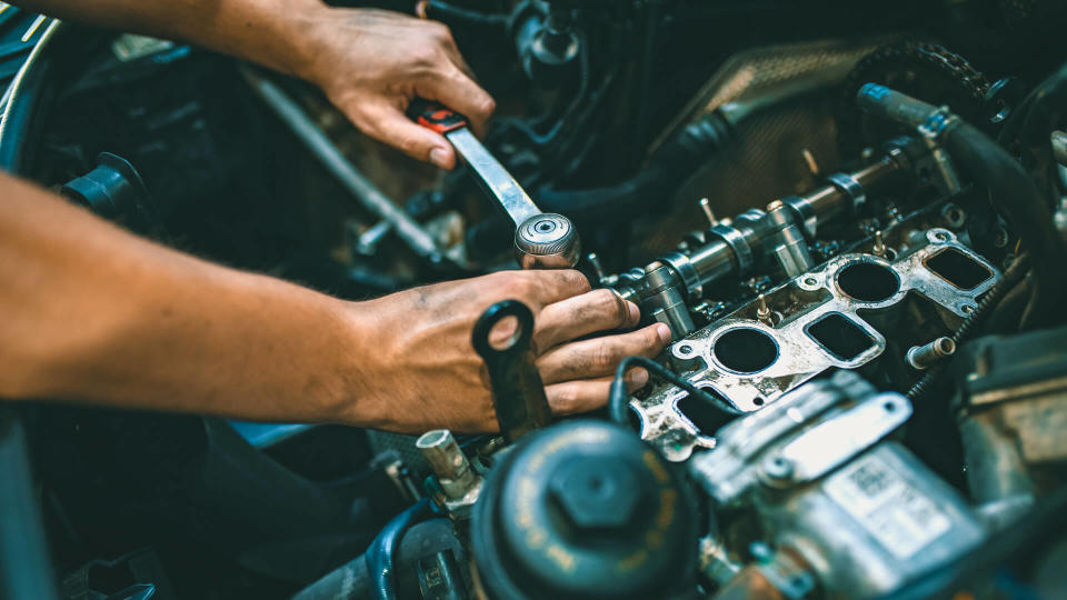 Car mechanic man at the garage fixing the engine.