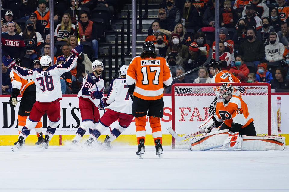 Columbus Blue Jackets' Boone Jenner (38), Oliver Bjorkstrand (28) and Sean Kuraly (7) celebrate past Philadelphia Flyers' Zack MacEwen (17) and Carter Hart (79) after Bjorkstrand's goal during the second period of an NHL hockey game, Thursday, Jan. 20, 2022, in Philadelphia. (AP Photo/Matt Slocum)