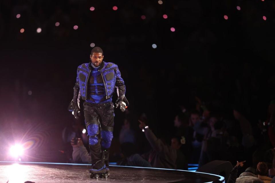 Usher performs onstage in a blue outfit during halftime.