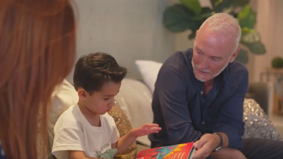 Simon Nicholls reads with his 3-year-old son, Sylver, at his home in Miami. - CNN