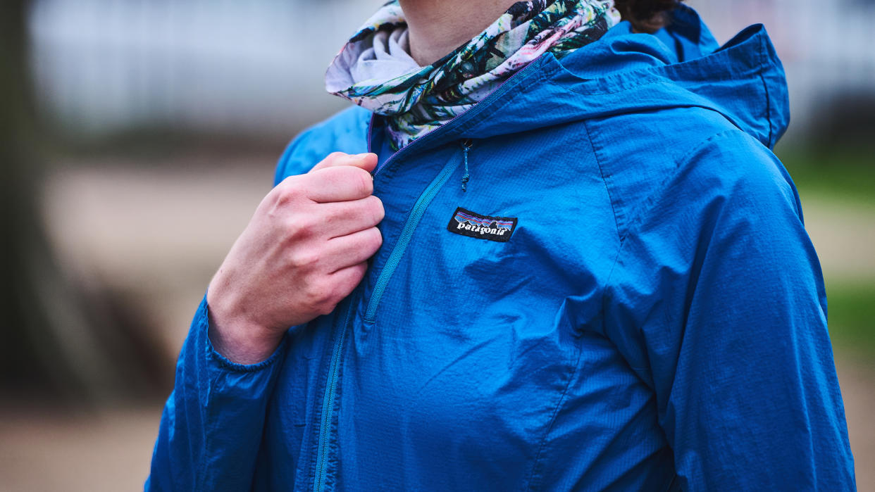  Woman fastening Patagonia Houdini jacket. 