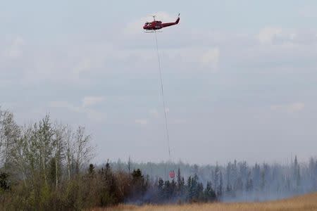 A helicopter battles a wildfire near Fort McMurray, Alberta, Canada, May 8, 2016. REUTERS/Chris Wattie