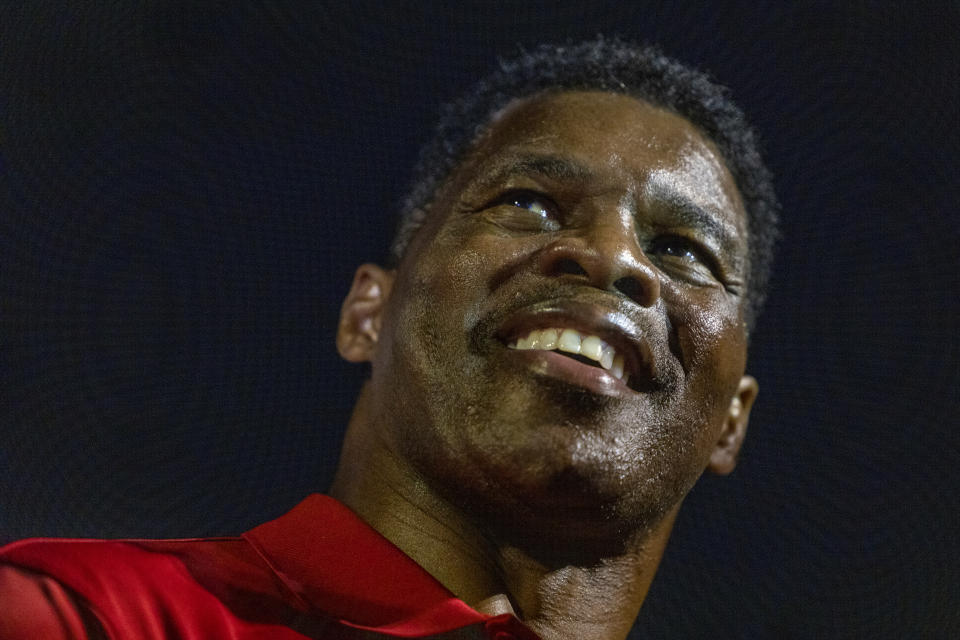 Herschel Walker, his skin glistening with sweat, grins broadly as he greets supporters.
