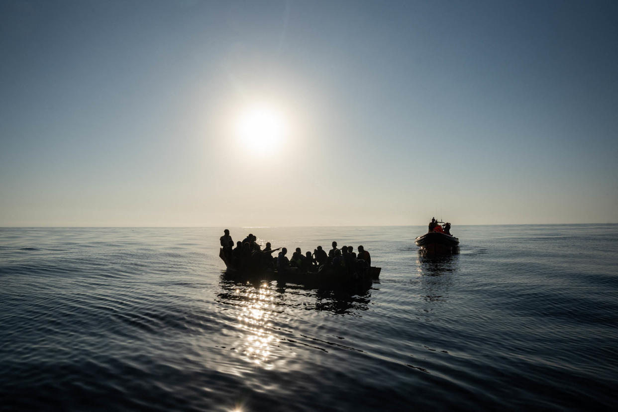 Quelques-uns des 266 migrants traversant la Méditerranée sur de petites embarcations avant d'être secourus par des membres de l'ONG espagnole Proactiva Open Arms (R) au large des côtes libyennes, le 3 août 2023. (Photo de Matias CHIOFALO / AFP)