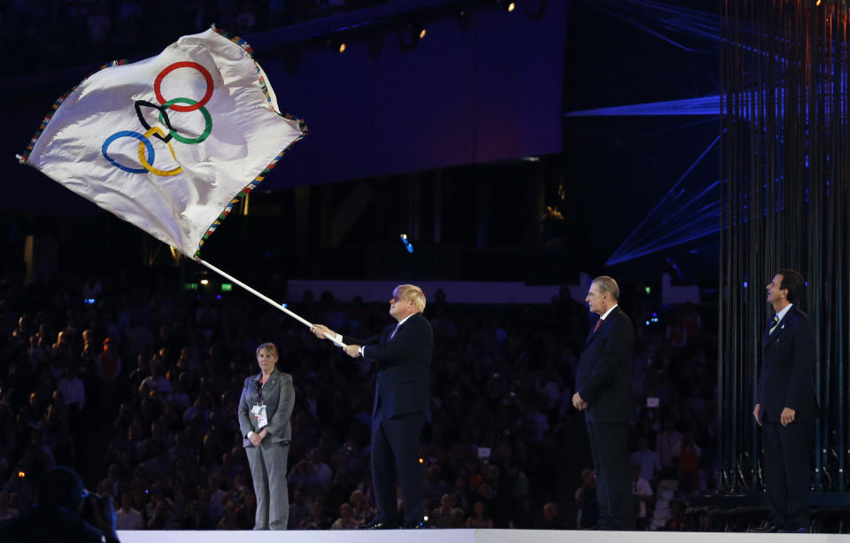 FILE - London mayor Boris Johnson, second from left, waves the Olympic flag as President of the International Olympic Committee Jacques Rogge, center, and Eduardo Paes, mayor of Rio de Janeiro look on during the Closing Ceremony at the 2012 Summer Olympics, Sunday, Aug. 12, 2012, in London. British media say Prime Minister Boris Johnson has agreed to resign on Thursday, July 7 2022, ending an unprecedented political crisis over his future. (AP Photo/Matt Dunham, File)