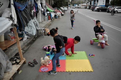 Children play near their families' tents set up on a street outside Eleonas refugee camp in Athens