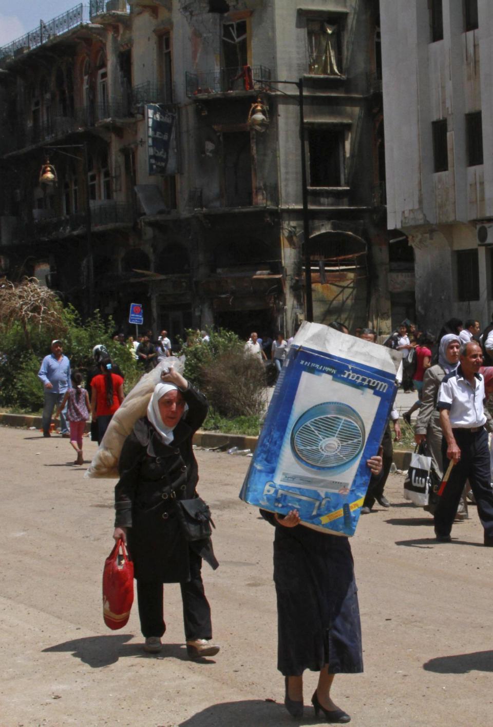 Residents carry some of their belongings in the al-Hamidiyeh neighborhood of Homs, Syria, Saturday, May 10, 2014. Thousands of Syrians streamed into war-battered parts of the central city of Homs for the first time in nearly two years Saturday, many making plans to move back just days after rebels surrendered their strongholds to pro-government forces. The surrender deal is widely seen as a victory for Assad weeks ahead of a presidential election on June 3 that he is expected to win, giving him a mandate to continue his violent crackdown on rebels in the Syrian civil war, which activists say has killed more than 150,000 people. (AP Photo)