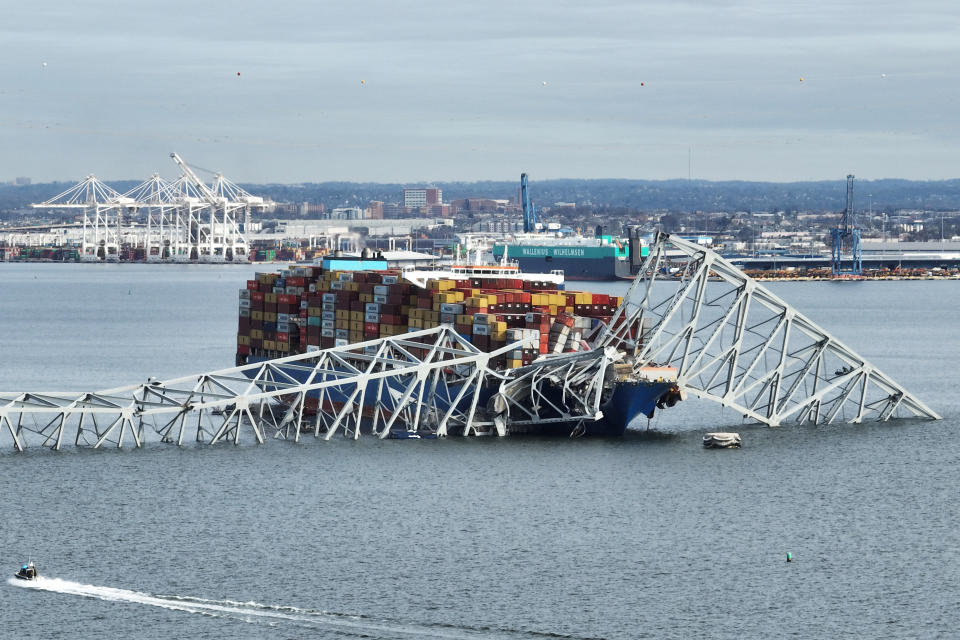 Cargo ship crashed into a collapsed bridge over water with emergency services visible