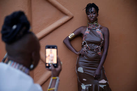 A woman takes a picture of a model behind the scenes of a fashion show featuring African fashion and culture as part of a gala marking the launch of a book called "African Twilight: The Vanishing Rituals and Ceremonies of the African Continent" at the African Heritage House in Nairobi, Kenya March 3, 2019. REUTERS/Baz Ratner