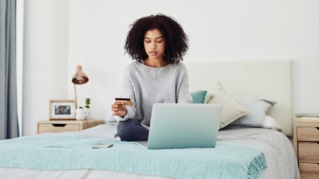 Cropped shot of an attractive young woman sitting on her bed at home and using her laptop for online shopping.