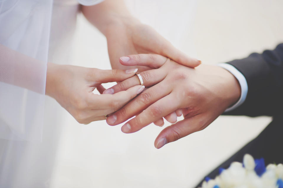 Midsection Of Couple Exchanging Wedding Ring.