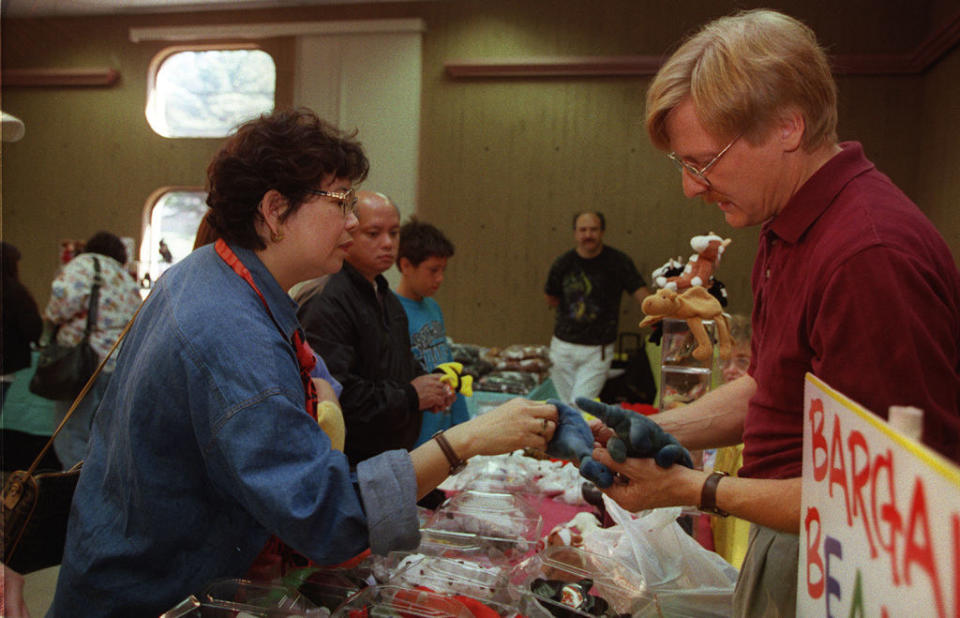 A woman inspects 2 dinosaur beanies