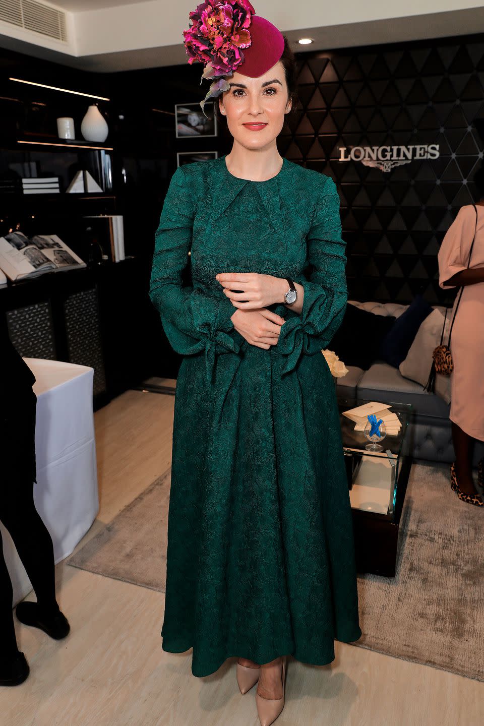 <p>Michelle Dockery paired her jade green dress with a fuchsia hat and Longines watch. </p>