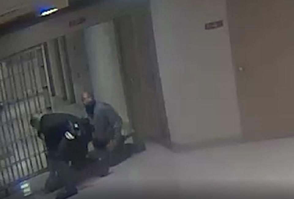 A screenshot from surveillance footage at 201 Poplar shows two correctional officers kneeling on Gershun Freeman's back. One officer would keep his knee on Freeman's back for almost six minutes.