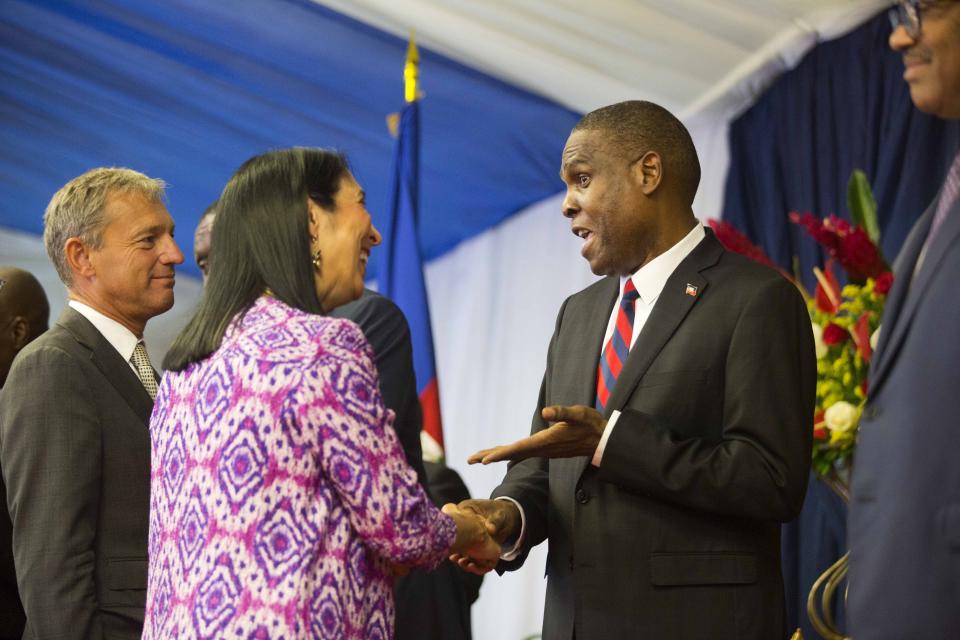 CORRECTS TO REMOVE EXACT NUMBER OF U.S. CONTRACTORS ARRESTED - FILE - In this Aug. 7, 2018 file photo, Haiti's Prime Minister Jean-Henry Ceant shakes hands with U.S. ambassador in Haiti, Michele Sison, at the National Palace in Port-au-Prince, Haiti. Neither the Haitian government nor the American ambassador has offered any explanation of the Feb. 17, 2019 arrest of a group of U.S. contractors’ or the reason for their release, which appeared to violate Haitian criminal procedure. (AP Photo/Dieu Nalio Chery, File)