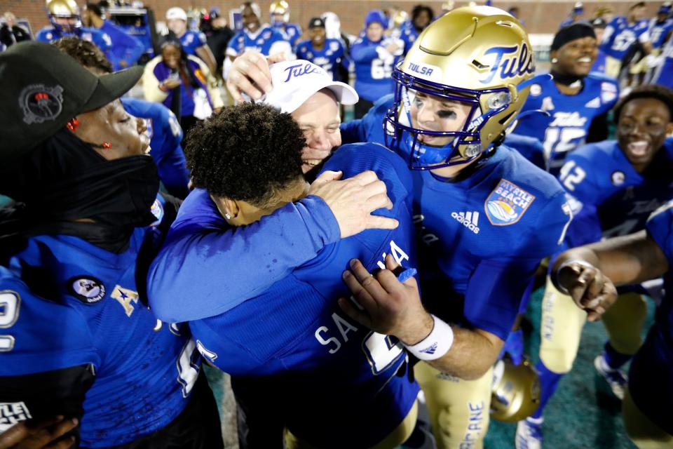 Tulsa's JuanCarlos Santana hugs head coach Philip Montgomery as quarterback Davis Brin, right, joins in the celebration Monday after they defeated Old Dominion in the Myrtle Beach Bowl in Conway, S.C.