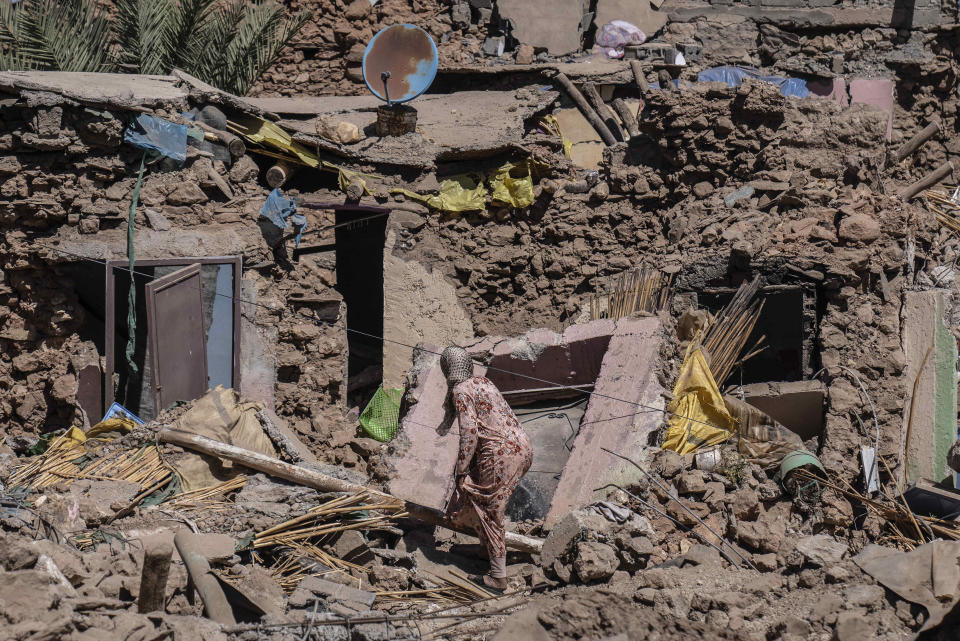 A woman tries to recover some of her possessions from her home which was damaged by the earthquake in the village of Tafeghaghte, near Marrakech, Morocco, Monday, Sept. 11, 2023. Rescue crews expanded their efforts on Monday as the earthquake's death toll continued to climb to more than 2,400 and displaced people worried about where to find shelter. (AP Photo/Mosa'ab Elshamy)