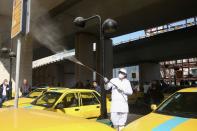 A member of the medical team wears a protective face mask, following the coronavirus outbreak, as he sprays disinfectant liquid to sanitise a taxi station in Tehran