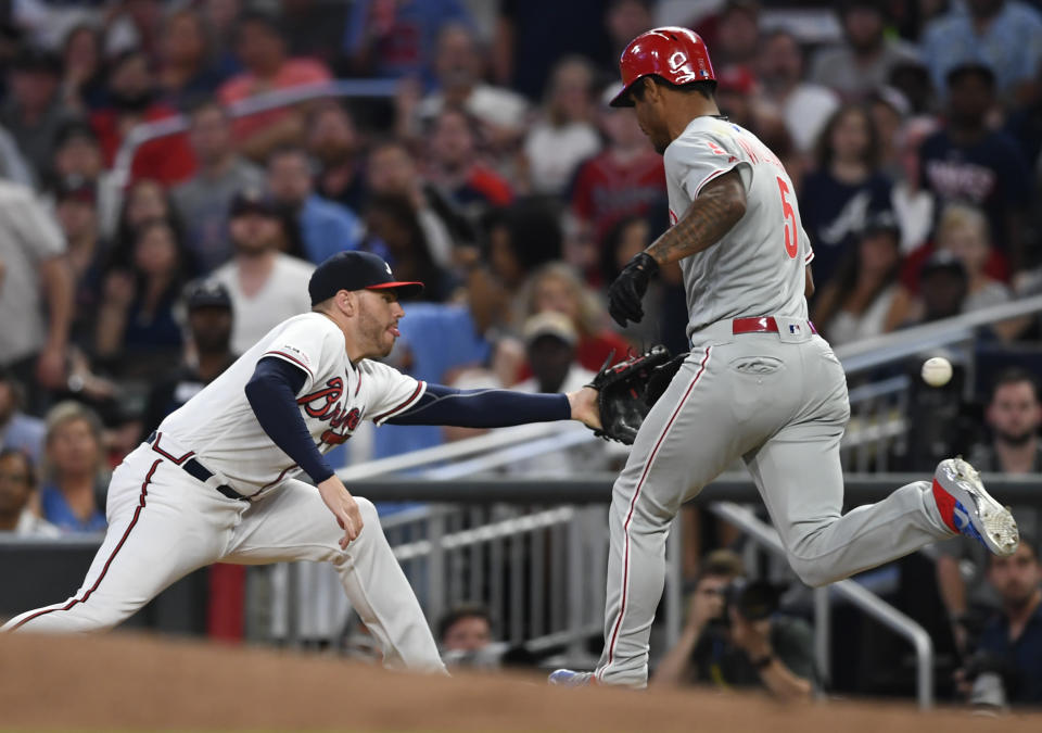 Philadelphia Phillies' Nick Williams, right, cannot beat the throw from Atlanta Braves catcher Tyler Flowers to first baseman Freddie Freeman, left, for an out during the fifth inning of a baseball game Saturday, June 15, 2019, in Atlanta. (AP Photo/John Amis)