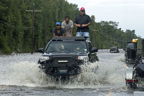 Motorists on Highway 190 drive through deep water through Holden, La., after heavy rains.