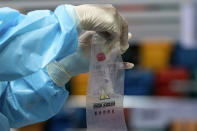 A medical professional puts a swab sample in a ziplock bag at a makeshift testing site in the Queen Elizabeth Stadium in Hong Kong Tuesday, Sept.1, 2020. Hong Kong began a voluntary mass-testing program for coronavirus Tuesday as part of a strategy to break the chain of transmission in the city's third outbreak of the disease. (Anthony Kwan /Pool Photo via AP)