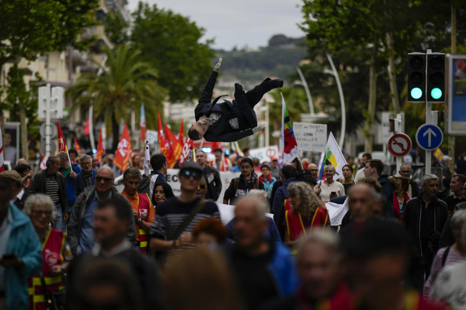 Protesters toss a puppet depicting President Emmanuel Macron during a demonstration in Cannes, southern France, Sunday, May 21, 2023. French unions are calling for demonstrations against President Emmanuel Macron's pension reform during the 76th edition of the Cannes Film Festival. (AP Photo/Daniel Cole)