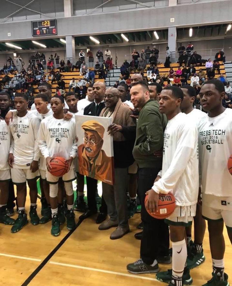 Willie "Roy" Ogletree, holding a portrait presented to him by Coach Steve Hall (to the left of Ogletree) and the entire Cass Tech boys basketball team, has been the official scorekeeper for Cass Tech's boys basketball teams since 1975.