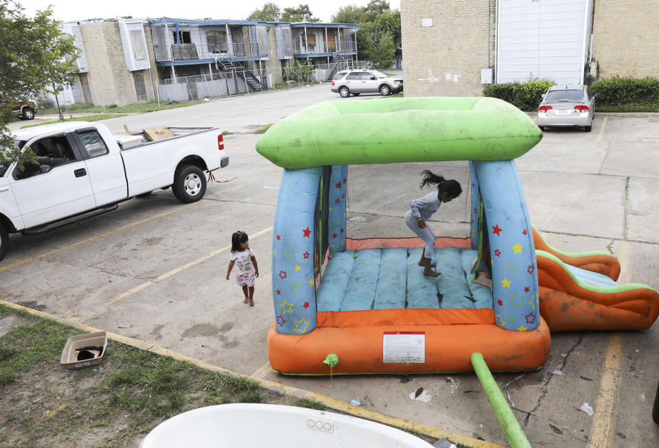 Monica Cruz, 7, jumps in an inflatable bouncy house as her neighbor Ashley Guerrero Monterrosa, 2, walks in the parking lot as residents clean up from Tropical Storm Harvey at Rockport Apartments. (Photo: Elizabeth Conley/Houston Chronicle)