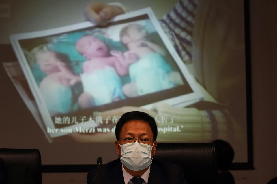 Xu Guixiang, a deputy spokesperson for the Xinjiang regional government, looks up near a slide showing a photo of Uighur infants during a press conference to refute accusations of genocide in Beijing, China. The Chinese official on Monday denied Beijing has imposed coercive birth control measures among Muslim minority women, following an outcry over a tweet by the Chinese Embassy in Washington claiming that government polices had freed women of the Uighur ethnic group from being "baby-making machines." (AP Photo/Ng Han Guan)