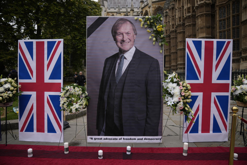 An image of British Member of Parliament David Amess is displayed opposite the Houses of Parliament in London, placed there as a memorial by supporters of the National Council of Resistance of Iran (NCRI), Monday, Oct. 18, 2021. British lawmaker David Amess was killed on Friday during a meeting with constituents at the Belfairs Methodist church, in Leigh-on-Sea, Essex, England. (AP Photo/Matt Dunham)