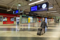 A woman with a suitcase walks crosses the empty S-Bahn platform at Munich Airport. (Photo by Peter Kneffel/picture alliance via Getty Images)