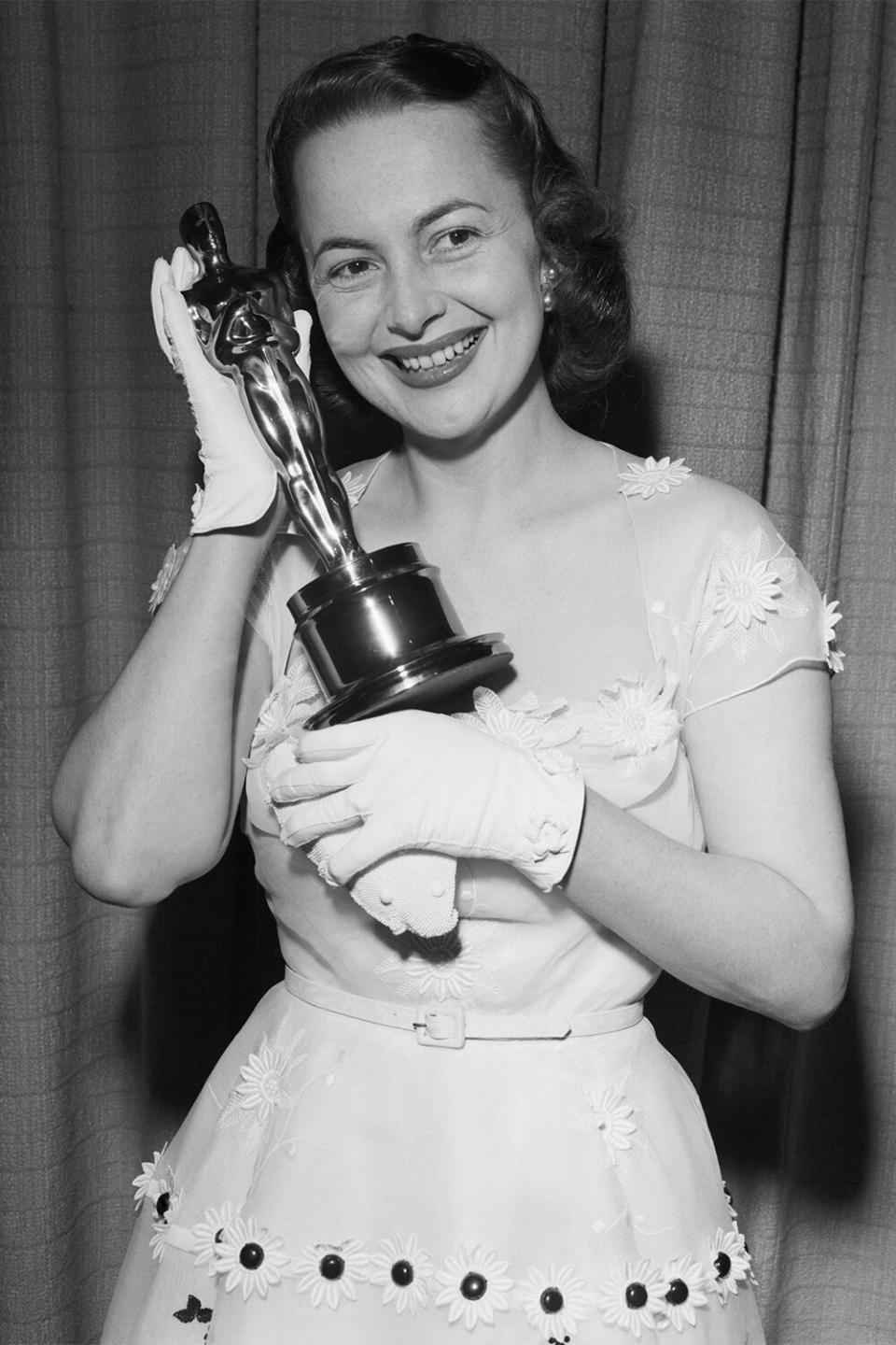 (Original Caption) 3/25/50-Hollywood, California: Actress Olivia De Havilland proudly displays her second "Oscar," awarded for her performance as the Best Actress of 1949 for her role in "The Heiress." Miss De Havilland also won top honors in 1946.