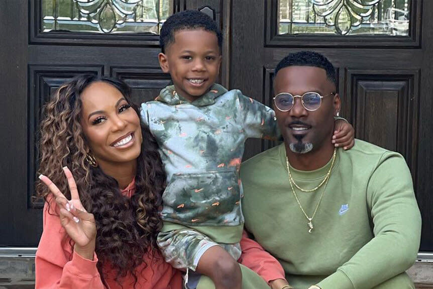 Sanya, Aaron, and Deuce pose together on a doorstep.