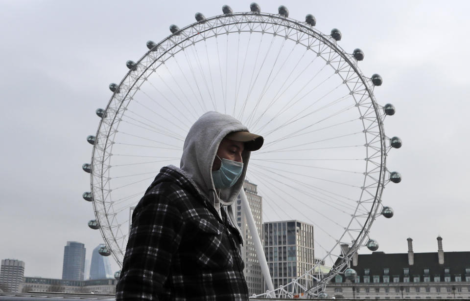 A man wearing a face covering walks past the London Eye in London, Friday, Jan. 8, 2021. Britain's Prime Minister Boris Johnson has ordered a new national lockdown for England which means people will only be able to leave their homes for limited reasons, with measures expected to stay in place until mid-February. (AP Photo/Frank Augstein)