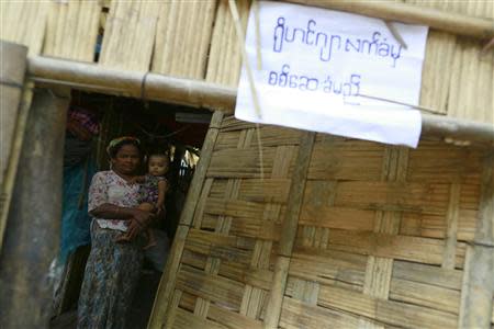 A Rohingya woman carries a child inside a temporary shelter with a sign displayed outside, as the government embarks on a national census at a Rohingya refugee camp in Sittwe, the capital of Rakhine State April 1, 2014. REUTERS/Soe Zeya Tun