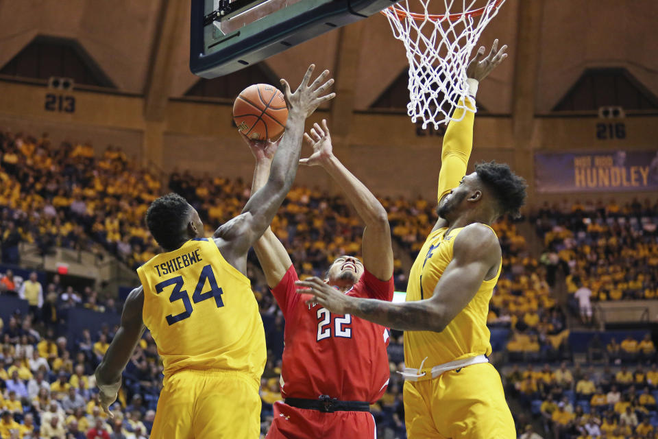 Texas Tech forward TJ Holyfield (22) goes to shoot as he is defended by West Virginia forwards Oscar Tshiebwe (34) and Derek Culver (1) during the first half of an NCAA college basketball game Saturday, Jan. 11, 2020, in Morgantown, W.Va. (AP Photo/Kathleen Batten)