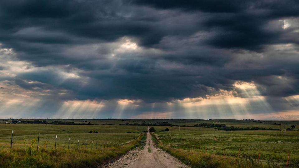 Sunbeams stream through passing storm clouds over a minimally maintained road in the Flint Hills near Cottonwood Falls on Sunday.