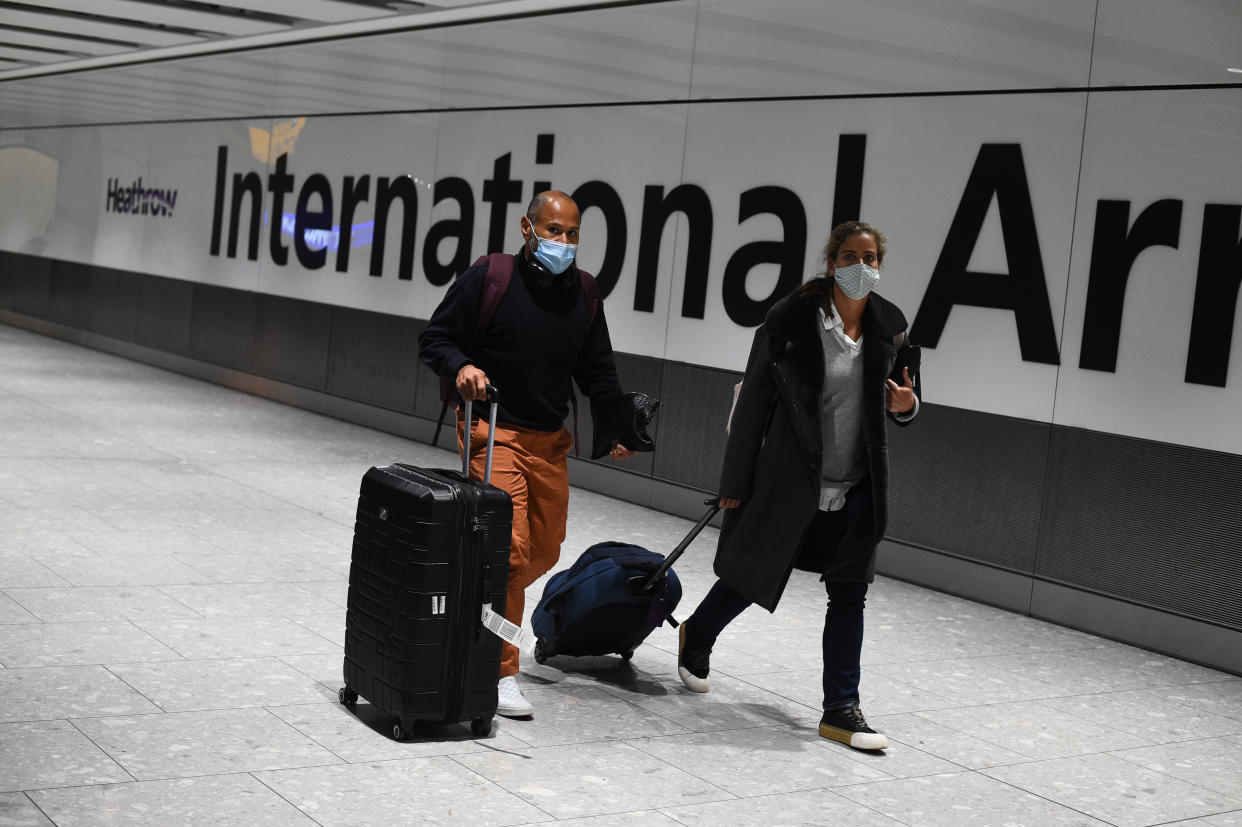 Passengers walk with luggage through the Arrival Hall of Terminal 5 at London's Heathrow Airport after arriving into the UK following the suspension of the travel corridors. Passengers arriving from anywhere outside the UK, Ireland, the Channel Islands or the Isle of Man must have proof of a negative coronavirus test and self-isolate for 10 days. Picture date: Monday January 18, 2021.