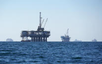 FILE - In this Oct. 5, 2021, file photo, cargo vessels are seen anchored offshore, sharing space with oil platforms, before heading into the Los Angeles-Long Beach port. A group of environmental organizations is demanding the Biden administration suspend and cancel oil and gas leases in federal waters off the California coast after a recent crude oil spill. The Center for Biological Diversity and about three dozen organizations sent a petition Wednesday, Oct. 20, 2021, to the Department of the Interior, arguing it has the authority to end these leases. (AP Photo/Eugene Garcia, File)