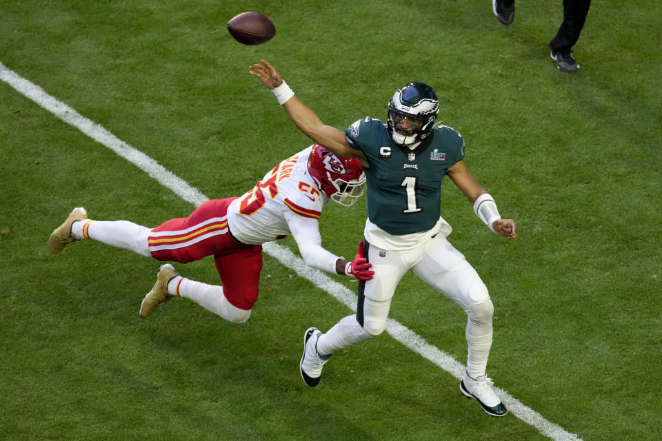 Philadelphia Eagles quarterback Jalen Hurts (1) throws the ball away before being tackled by Kansas City Chiefs defensive end Frank Clark (55) during the first half of the NFL Super Bowl 57 football game, Sunday, Feb. 12, 2023, in Glendale, Ariz. (AP Photo/Charlie Riedel)