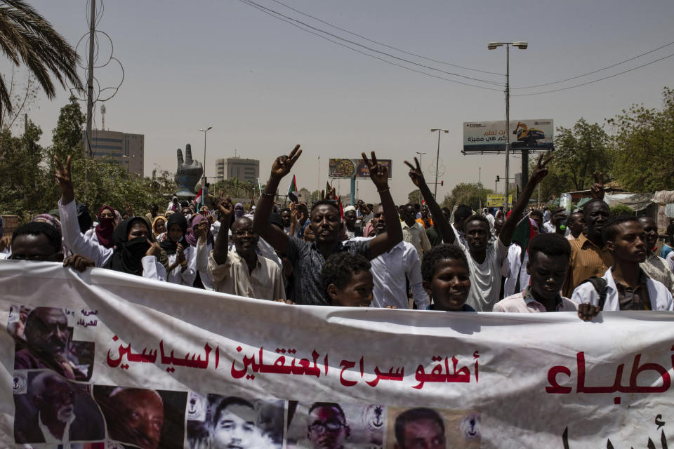 Protesters hold a banner calling for the release of political prisoners, during a march by members of the Sudanese medical profession syndicate, at the sit-in inside the Armed Forces Square, in Khartoum, Sudan, Wednesday, April 17, 2019. A Sudanese official and a former minister said the military has transferred ousted President Omar al-Bashir to the city's Kopar Prison in Khartoum. The move came after organizers of the street protests demanded the military move al-Bashir to an official prison. (AP Photos/Salih Basheer)