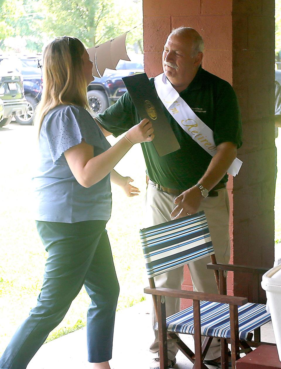 Molly Rafeld gives her father and retiring Ashland County EMA director Mark Rafeld a proclamation from the governor's office at his retirement picnic at Brookside West on Friday, July 29, 2022. TOM E. PUSKAR/ASHLAND TIMES-GAZETTE
