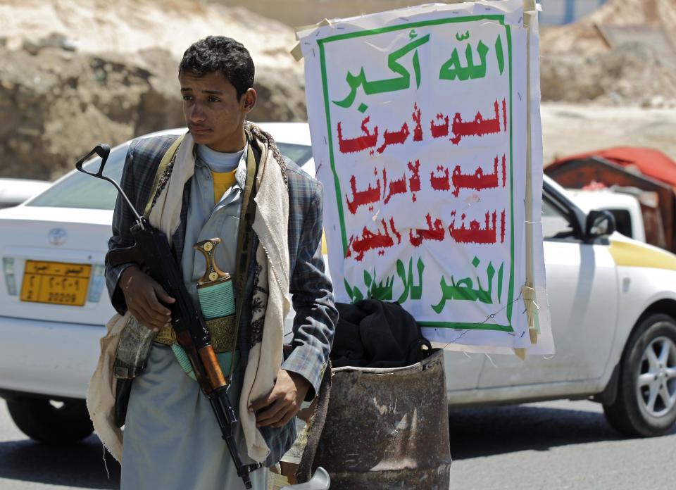 A Shi'ite Houthi rebel mans a checkpoint in Sanaa September 21, 2014. Shi'ite Houthi rebels and government forces fought for a fourth straight day in the Yemeni capital, residents said, despite the announcement of a U.N.-brokered agreement due to be signed later on Sunday. The banner reads "Allah is the greatest. Death to America, death to Israel, a curse on the Jews, victory to Islam". (REUTERS/Khaled Abdullah)