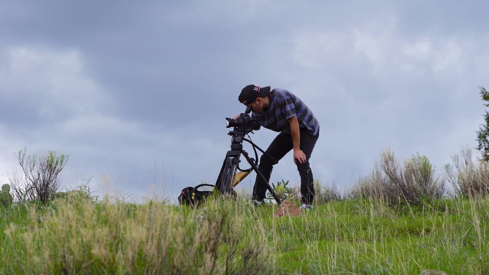 NMSU student filmmaker Noah Montes prepares his camera on a hilltop in the Gila Wilderness.